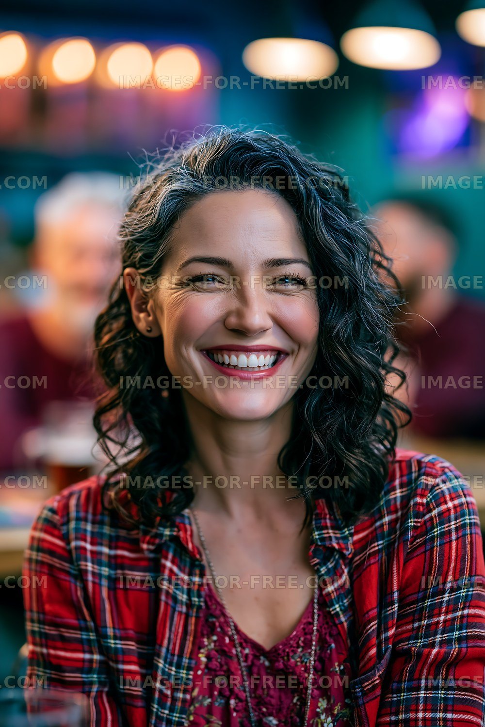 Smiling woman in plaid shirt inside busy cafe