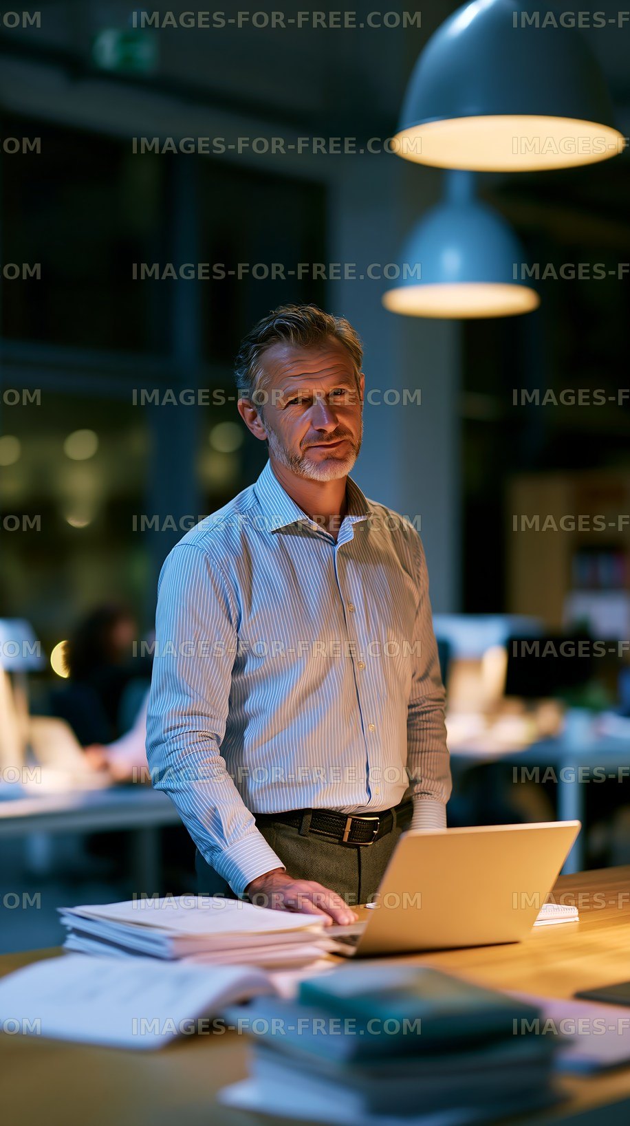 Man working at a laptop in an office during evening hours