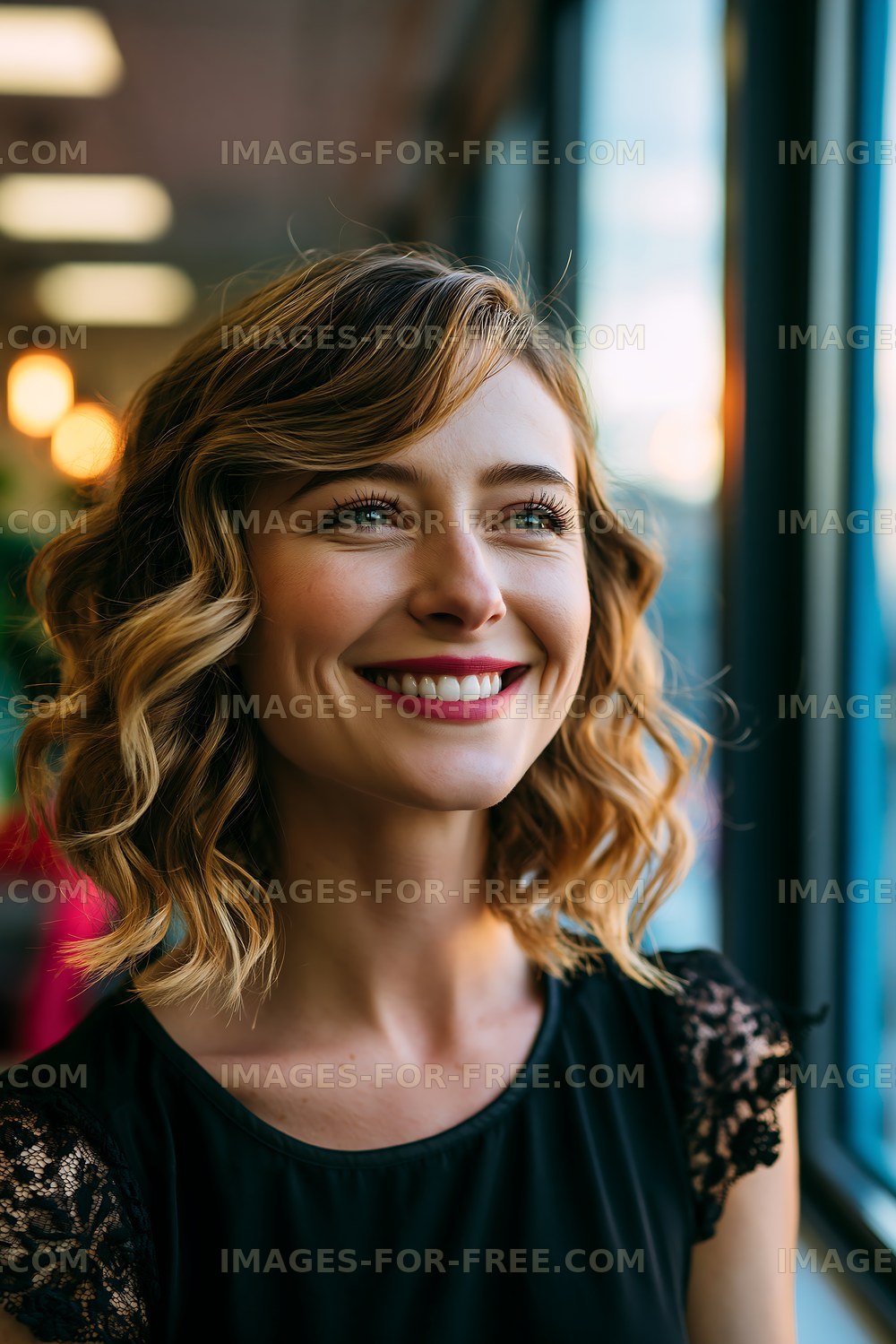 Woman smiling near large window during golden hour