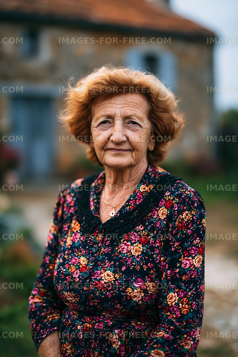 Elderly woman standing outdoors near a rustic stone house