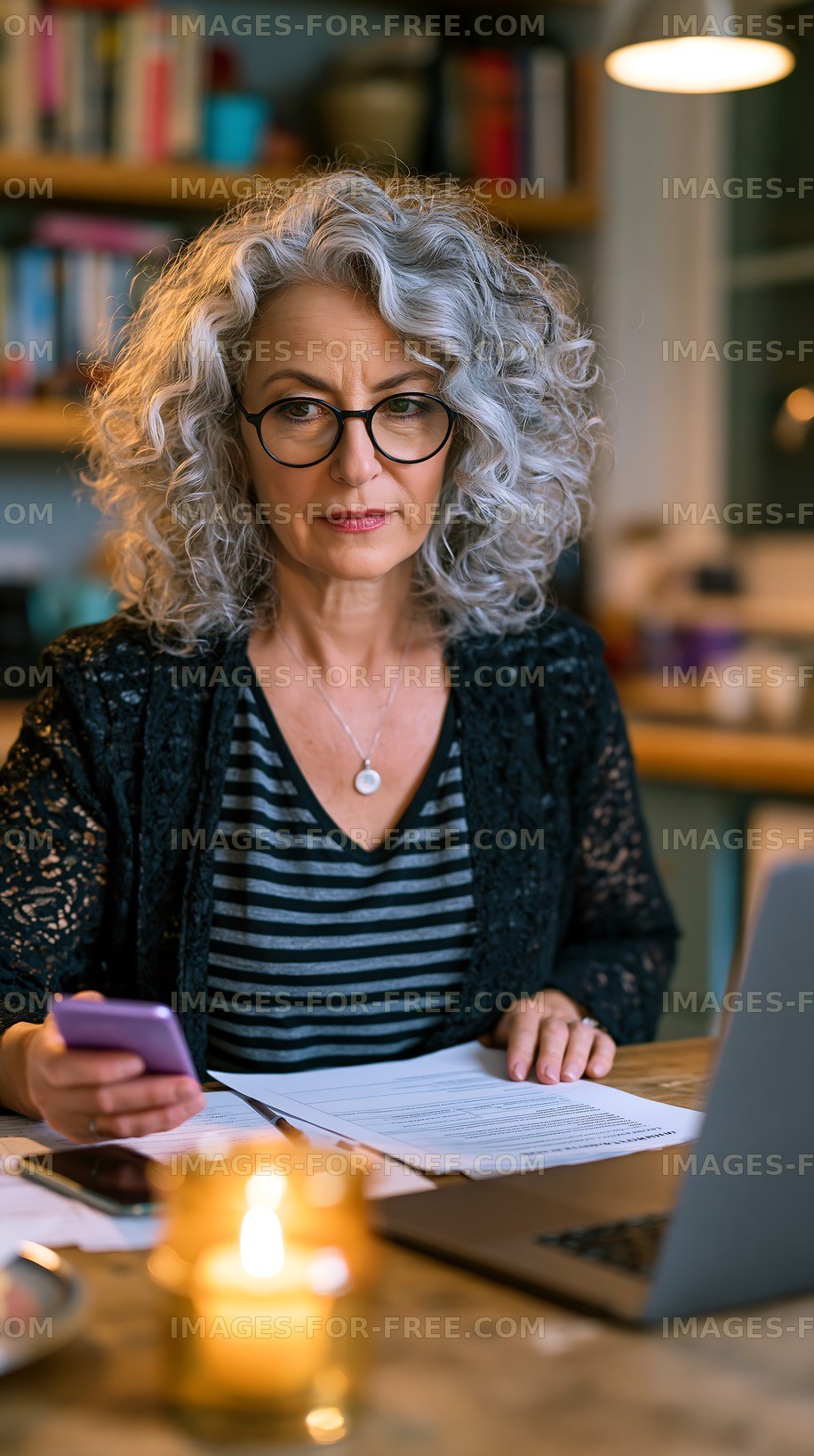 Woman working on documents at a table with a laptop and phone