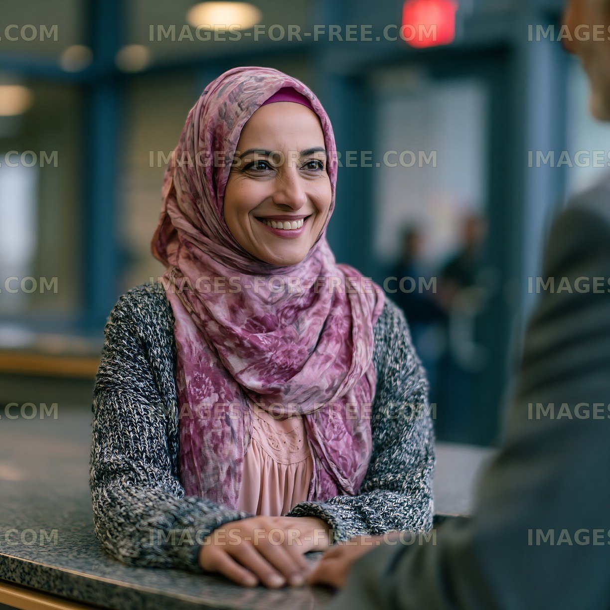 Woman in hijab smiling at a man in indoor setting