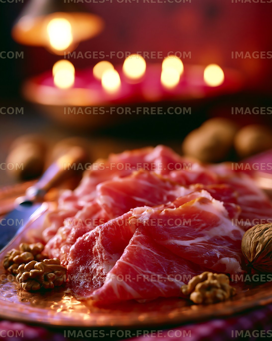 Sliced cured meat on a decorative plate with nuts nearby