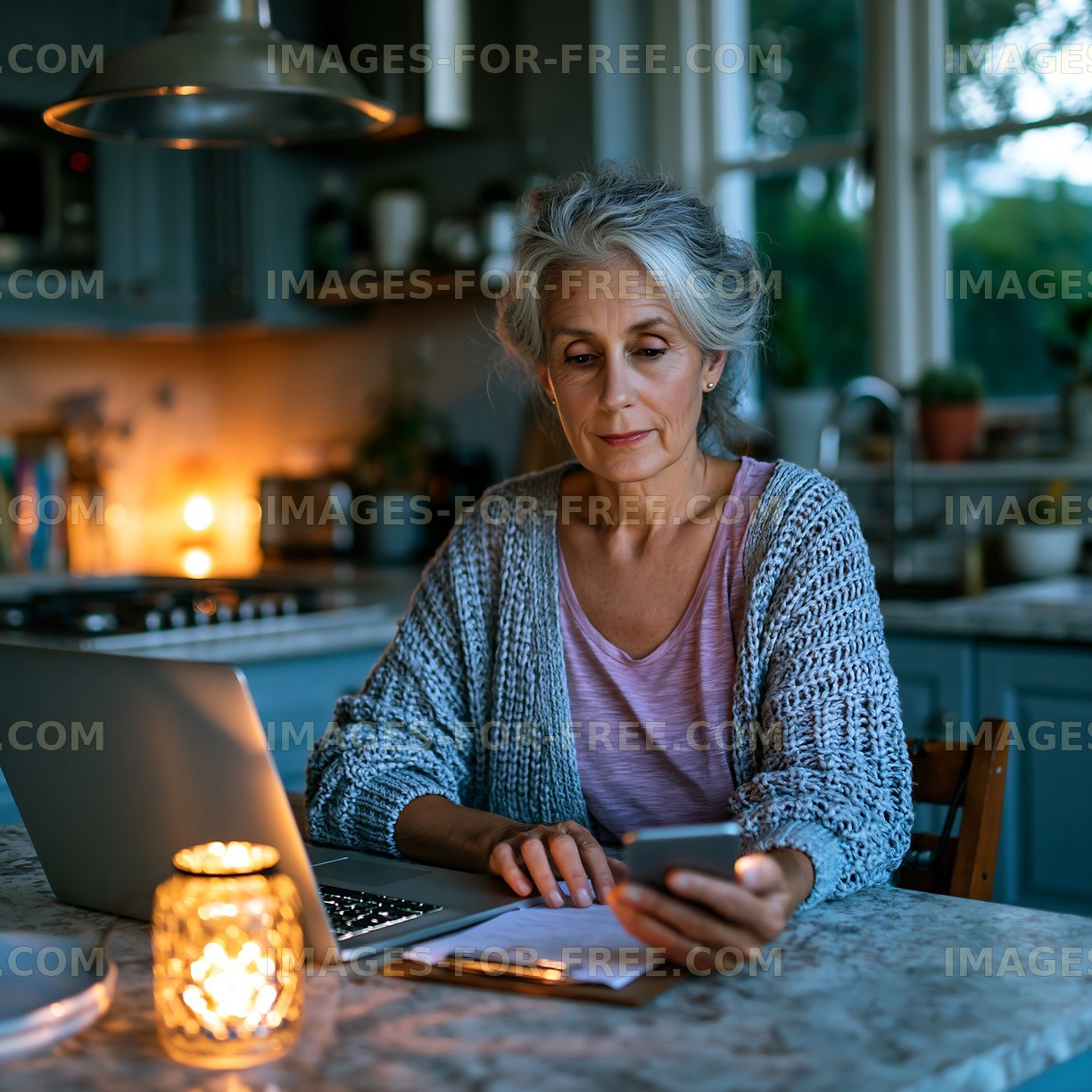 Woman using smartphone at kitchen table during evening