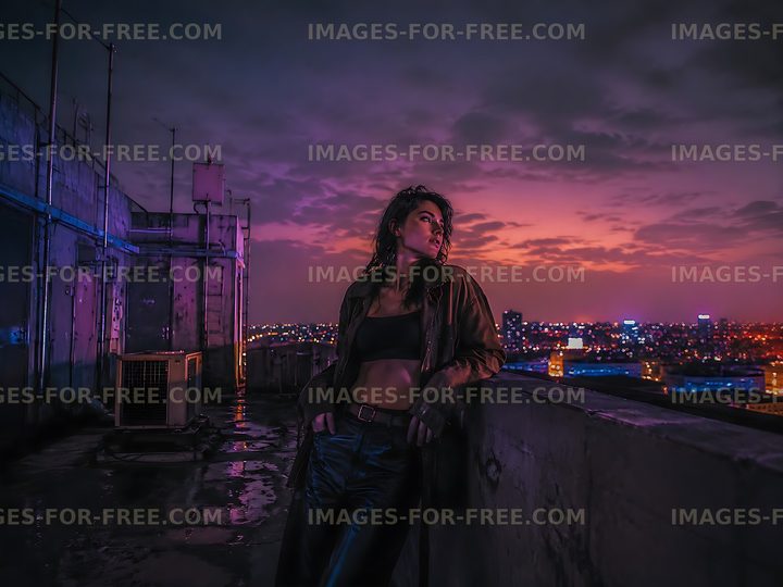 Woman leaning against rooftop wall during sunset