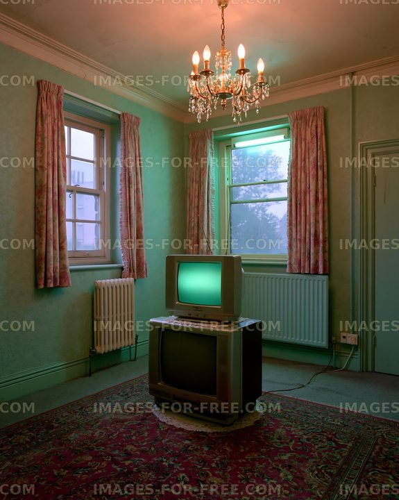 Old TV set in empty room with green light and chandelier
