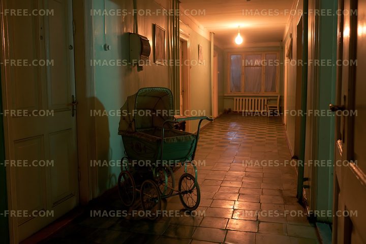 Old hallway with a vintage baby carriage at night